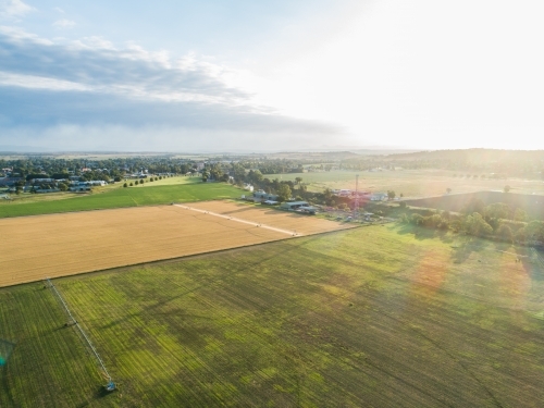 Sunlit farm paddock in good season with rain clouds on horizon - Australian Stock Image
