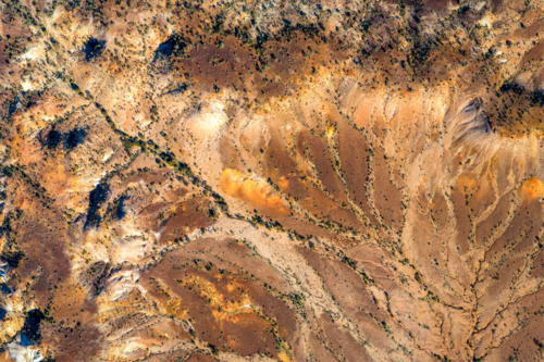 Sunlit gullies etched across warm, weathered hills - Australian Stock Image