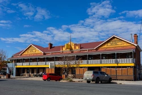 Sunlit pub hotel in country town of Gunning, New South Wales with cars parked outside - Australian Stock Image
