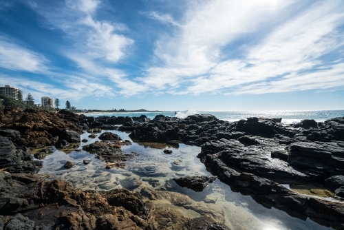 Sunlit rock pools along the coast at Coolum - Australian Stock Image