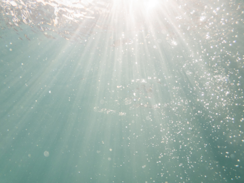 Sunrays underwater with sparkling bubbles in blue pool water  - Australian Stock Image