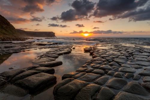 Sunrise sunlight across tessellated rocks Garie Beach