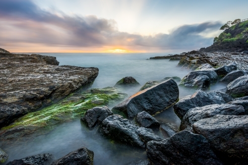 Sunrise with waves crashing on rocks - Australian Stock Image