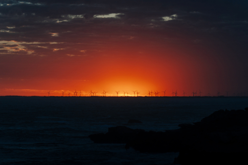 Sunset coast with wind turbines and glowing sky - Australian Stock Image