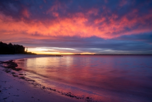 Sunset colours over a curve of beach - Australian Stock Image