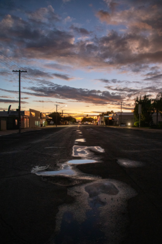 Sunset colours reflected from water on a small town street at dusk - Australian Stock Image