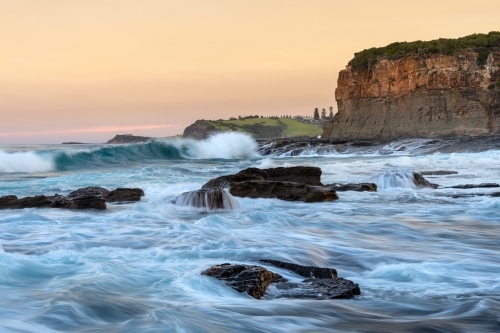 Sunset landscape of the ocean surging around a rocky headland