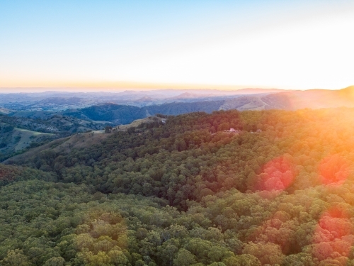 Sunset light over mountains covered in trees - Australian Stock Image