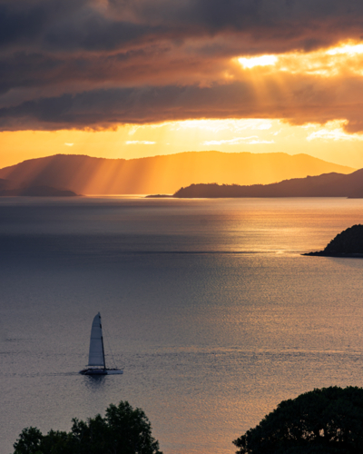 Sunset over the Whitsundays with a sailing boat in the Foreground as seen from Hamilton Island - Australian Stock Image