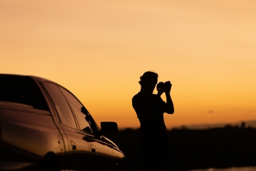 Sunset silhouette of man and car