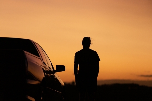 Sunset silhouette of man and car