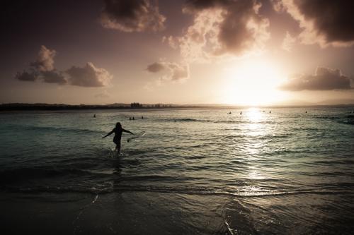 Sunset Surf at Byron Bay with female surfer - Australian Stock Image