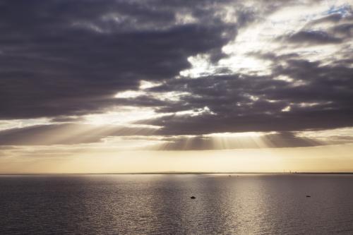 Sunset through clouds over the ocean - Australian Stock Image