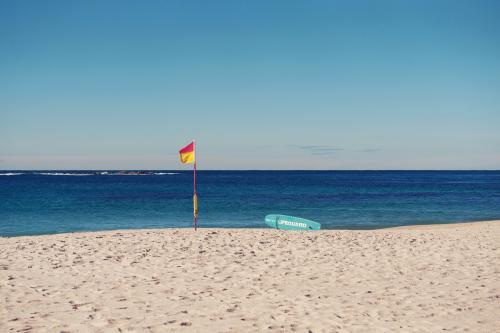 Surf lifesaving flag and paddleboard on Coogee, Sydney - Australian Stock Image
