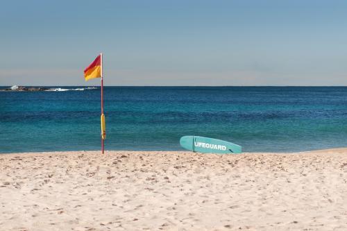 Surf lifesaving flag and paddleboard on Coogee, Sydney - Australian Stock Image