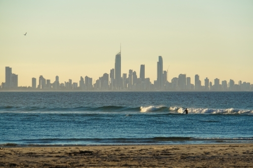 Surfer at sunset with Surfers Paradise in background