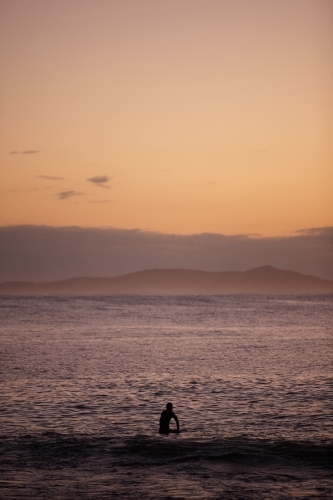 Surfer in ocean on sunrise - Australian Stock Image
