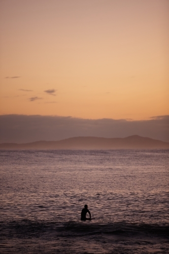Surfer in ocean on sunrise