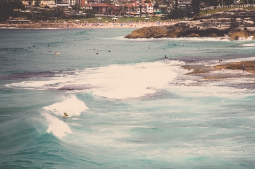 Surfer on a wave with beach in background - Australian Stock Image