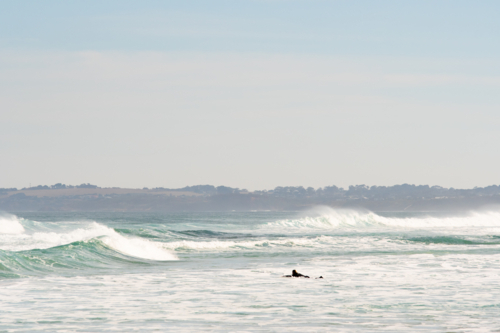 Surfer paddling out in big surf - Australian Stock Image