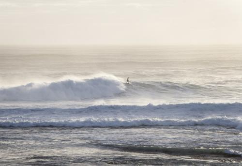 surfer riding a big wave in the distance - Australian Stock Image