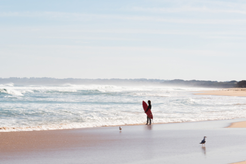 Surfer standing with board looking out to the surf - Australian Stock Image