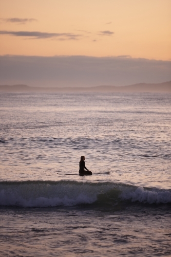 Surfer waiting for waves in ocean on sunrise