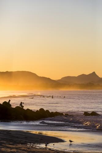 Surfers and people on rocks at sunset - Australian Stock Image