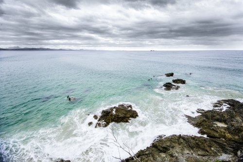Surfers by the rocks on a stormy day - Australian Stock Image