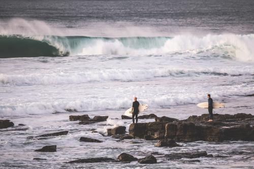 surfers getting ready to enter the ocean from rocks