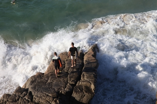 Surfers jumping off rocks