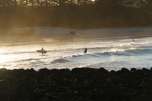 Surfers on beach at sunset - Australian Stock Image