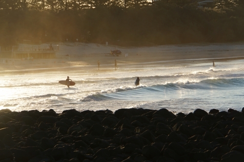 Surfers on beach at sunset