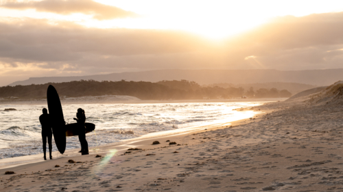 Surfers silhouetted at beach - Australian Stock Image