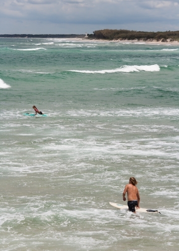 Surfers wading and padding out to a surf break - Australian Stock Image