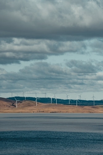Sustainable energy wind turbines on the rolling hills behind Lake George. - Australian Stock Image
