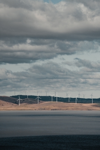 Sustainable energy wind turbines on the rolling hills behind Lake George. - Australian Stock Image