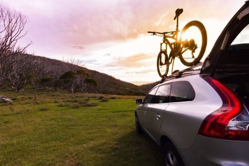 SUV and mountain bike with mountain view and sunflare - Australian Stock Image