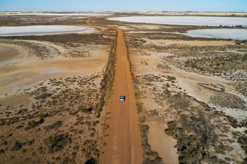 SUV driving on dirt road through dry salt lakes in Western Australia - Australian Stock Image