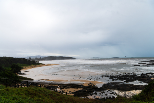 Sweeping View from headland with stormy sky, wild ocean waves, people, beaches and reefs - Australian Stock Image