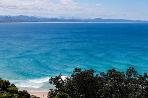 Sweeping view of blue ocean with mountains in the background - Australian Stock Image