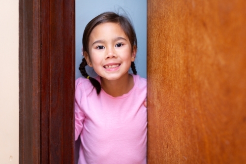 Sweet little girl looking out from half open door