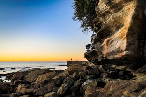 Swimmer at ocean baths against blue sky and rocky coastline - Australian Stock Image