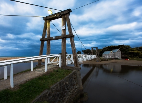 Swing bridge over river and sheds at dusk - Australian Stock Image