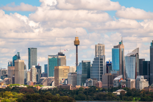 Sydney city skyline panorama with a plane taking off above while viewed across the harbour - Australian Stock Image