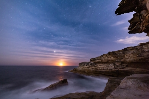 Sydney coastal cliffs by night with moonrise and light high clouds