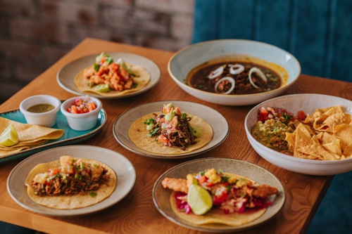 Tacos and Sides Served on a Wooden Table in a Cosy Restaurant Setting - Australian Stock Image