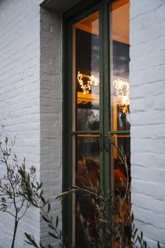 Tall narrow window with green frame and warm lights - Australian Stock Image