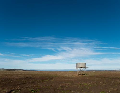 Tank stand in a treeless paddock against blue sky