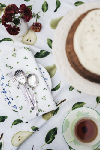 Tea, cake, and cutlery resting on patterned cloth in the soft outdoor light. - Australian Stock Image